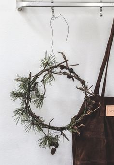 a brown bag hanging on a wall next to a tree branch and pinecone