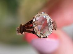 a close up of a person holding a ring with an oval shaped diamond in it