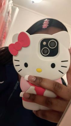 a woman holding up a cell phone case with a hello kitty on it's face