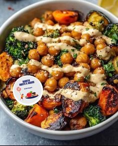 a bowl filled with broccoli, carrots and chickpeas covered in sauce