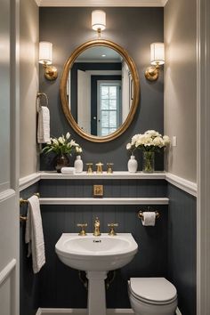 a white toilet sitting next to a bathroom sink under a round mirror in a bathroom