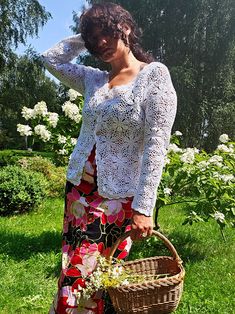 a woman standing in the grass holding a basket