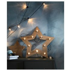 a lighted star on top of a table next to a blue wall with lights in the shape of stars