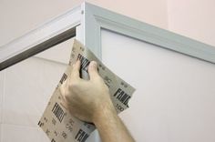 a man is working on the side of a wall with some tape and a screwdriver