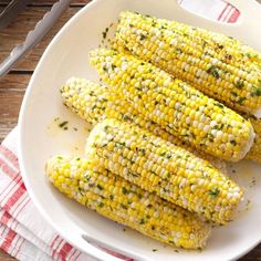 grilled corn on the cob with herbs and seasoning in a white bowl