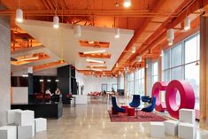 an office with large windows and colorful letters on the floor, along with chairs and couches