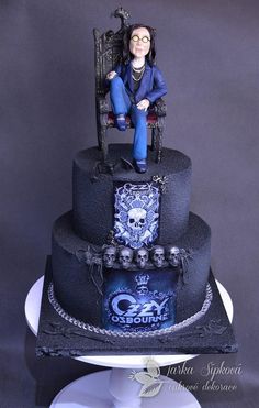 a cake with a woman sitting on top of it and skull decorations around the edges