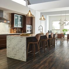 a large kitchen with wooden floors and marble counter tops, along with bar stools