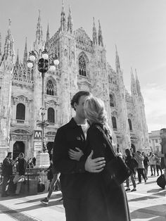 a man and woman kissing in front of a cathedral