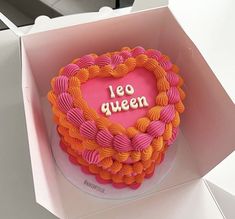 a heart shaped cake with the words leo queen written on it in pink and orange icing