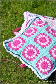 a crocheted blanket laying on the grass