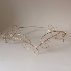 a tiara made out of gold wire on a white surface with a small diamond in the center