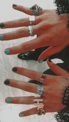 four hands with different rings on them, one is blue and the other has black nails