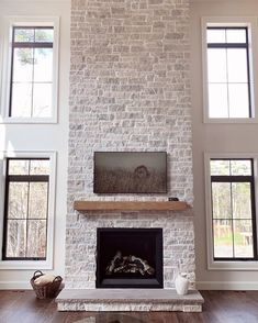 a living room filled with furniture and a fire place in front of two large windows