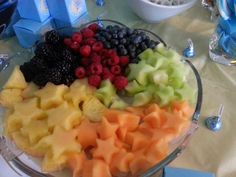 there are many different types of fruit in the bowl on the table, including grapes, pineapples, blueberries and raspberries