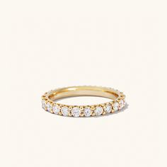 a yellow gold band with white diamonds on the top and bottom, set against a plain background