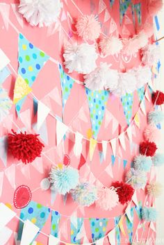 a party decoration with tissue pom poms and streamers on a pink background