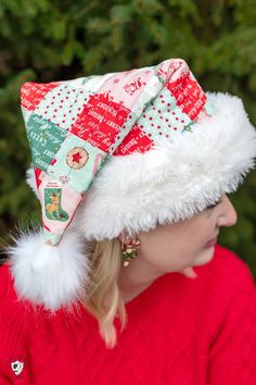 a woman wearing a red sweater and a white hat with pom - poms