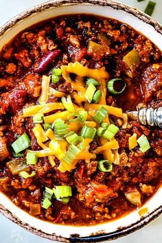 a bowl filled with chili and cheese on top of a table