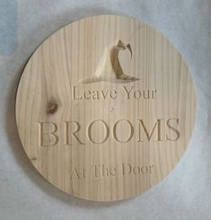 a wooden sign that says leave your brooms at the door