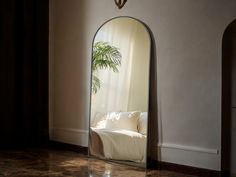 a large mirror in the corner of a room with a couch and potted plant