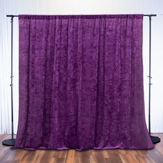 a purple curtain hanging on the side of a wall in front of a wooden floor