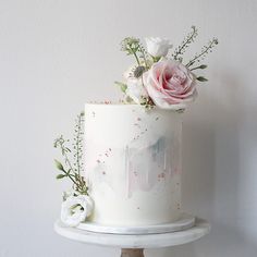 a white cake with pink flowers and greenery on top