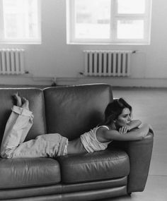 a woman laying on top of a leather couch