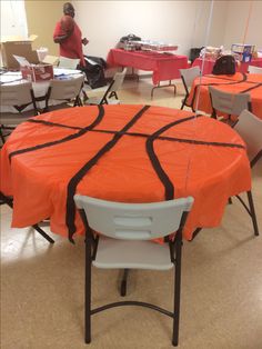 an orange and black basketball themed tablecloth on a round table with chairs around it