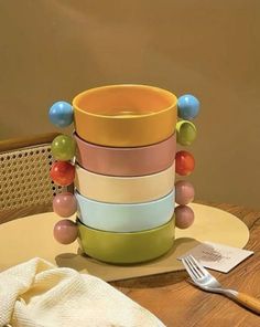 a stack of multicolored cups sitting on top of a table next to a fork