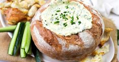 a plate topped with bread covered in cream cheese and green onions next to other food items