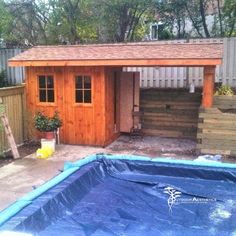 a small wooden shed with a pool in the middle and a blue tarp around it