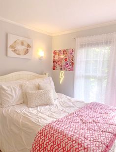 a bed with white sheets and pink comforter in a bedroom next to a window