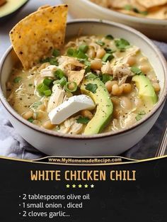 a bowl of white chicken chili with avocado and tortilla chips on the side