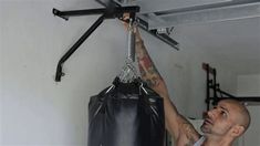 a man with tattoos on his arm holding up a punching bag