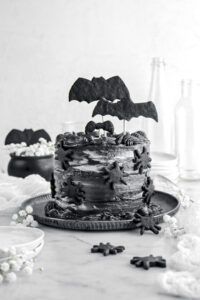 a black and white photo of a halloween cake with bats on top, surrounded by other decorations