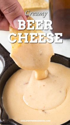 a person dipping cheese into a skillet filled with creamy beer sauce for an appetizer