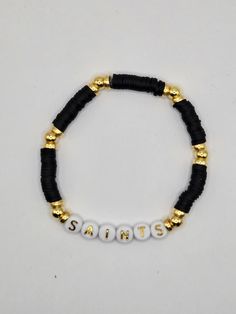 New Orleans Saints Stretch Bracelets made with Black Heishi Beads, Gold Spacers Beads, and Plastic Alphabet Beads. Black Heishi Beads Bracelet With Colorful Beads, Black Heishi Beads Beaded Bracelets, Black Heishi Beads Bracelet, Adjustable Black Heishi Beads Bracelets, Black Beaded Friendship Bracelets With Heishi Beads, Black Beaded Heishi Friendship Bracelets, Black Bracelets With Letter Beads For Beach, Black Letter Beads Bracelet For Beach, Black Beaded Name Bracelet With Round Beads