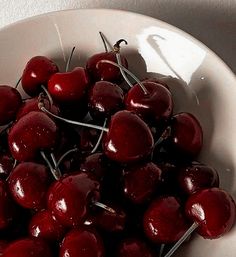 a white bowl filled with cherries on top of a table