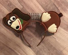 a brown and white monkey ears headband on top of a wooden floor next to a hair comb