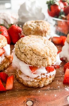 strawberry shortcakes on a cutting board with strawberries in the background and powdered sugar on top