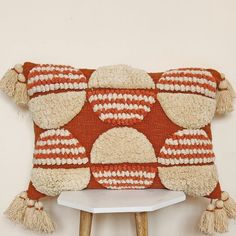 an orange and white pillow with tassels on it