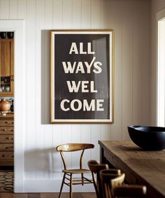 a black and white poster hanging on the wall above a wooden table with two chairs