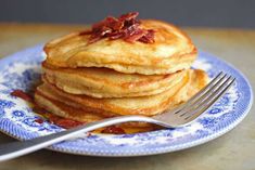 a stack of pancakes on a blue and white plate with a fork next to it