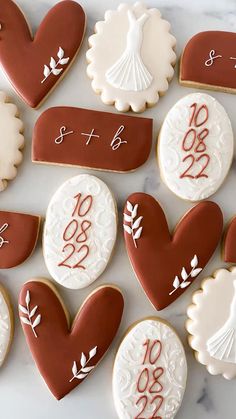 decorated cookies arranged in the shape of heart and wedding date, on a marble surface