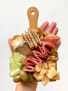 a hand holding a sandwich made out of different types of meats and cheeses