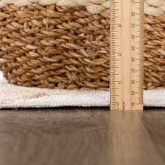 a close up of a wooden floor with a measuring tape on it and a basket in the background