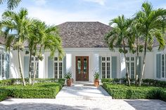 a white house with blue shutters and palm trees