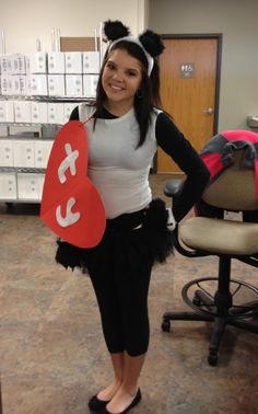 a woman is standing in an office with a heart shaped sign on her chest and black tutu