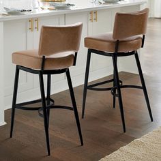 two brown bar stools sitting in front of a counter